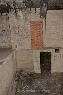 V levé části fotografie je betonová podlaha haly. Ve středu fotografie zazděný dveřní otvor před budovu. Proč byl postaven a následně zazděn to nedokážu odpovědět.
