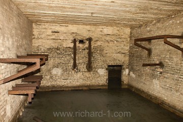 Zatopená místnost č. 97, pohled ze závalu v páteřní chodbě D. Na stěnách jsou ocelové závěsy pro dnes již těžko určitelné zařízení.
