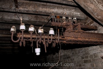 Nosník a porcelánové izolátory. V podzemí byl kromě osvětlení i rozvod telefonních drátů.