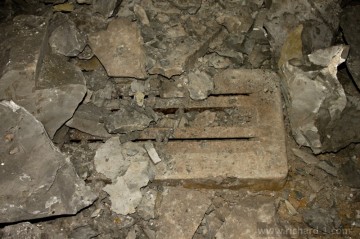 Pod opadaným vápencem, lze spatřit těžko zařaditelnou „mřížku“, zapuštěnou do betonového základu