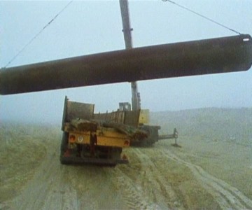Jeřáb sundává z nákladního auta ocelovou rouru pro vypažení vrtu.
