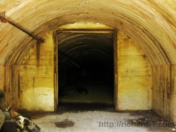 pohled od vstupní brány do krátké chodbičky s betonovou příčkou. Dál se již nachází spleť podzemních hal.