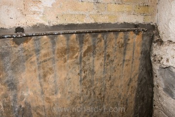 Na jedné ze stěn toalet, jsou doposud znatelné stopy po tekoucí oplachové vodě.