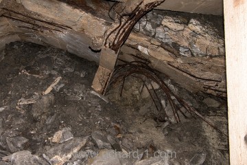 Rozlámané, železobetonové nosníky stropu jsou obklopeny směsí mokrého jílu a kamení.
